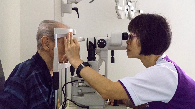 Optometrist conducting eye exam for elderly